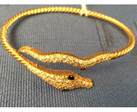 A contemporary diamond and sapphire serpent bangle, of cross over design, the head with sapphire eyes and pave set with 48 br