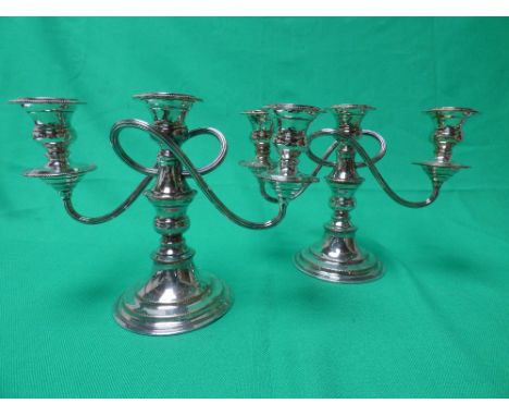 A pair of silver on copper three light candlesticks on circular loaded base. 18cm high