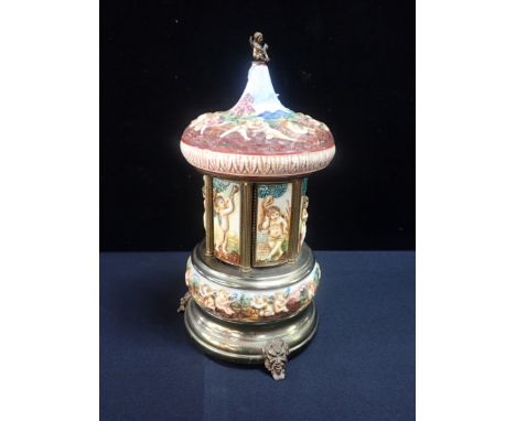 AN ITALIAN KITSCH CIGARETTE DISPENSER, WITH NAPLES STYLE CERAMIC BODY in brass frame, clockwork action opening whilst playing