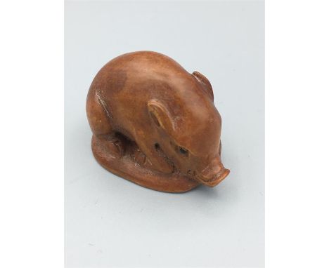 A Carved wooden netsuke in the horm of a pig signed to the base