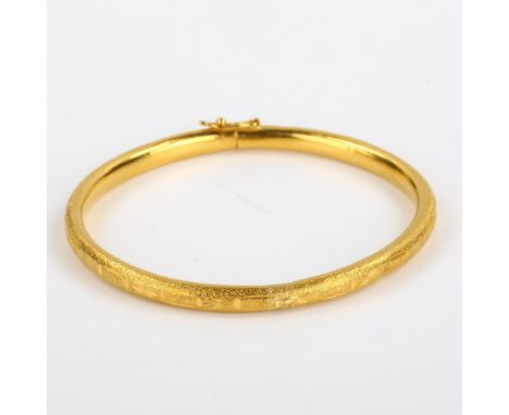 A Chinese 9999 gold hinged bangle, textured and engraved design, band width 4.4mm, internal diameter 5.5cm, 15.9gNo damage or