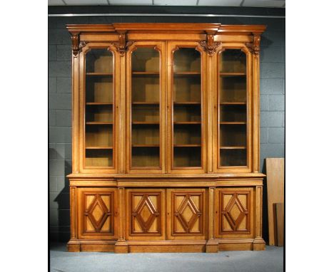 A Victorian blonde oak breakfront library bookcase - late 19th century, with applied scroll and leaf carved bracket mouldings