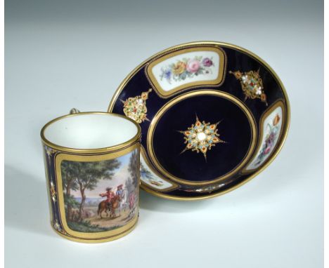 A 19th century 'Sevres' jewelled bleu de Roi coffee can and saucer, the former painted with two landscape panels flanking the