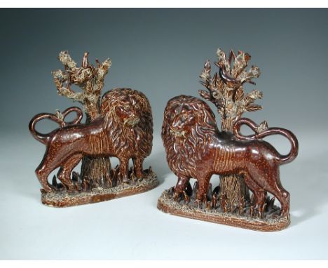 A pair of 19th century brown salt-glazed mantelpiece lions, probably Yorkshire, both standing before trees applied with birds