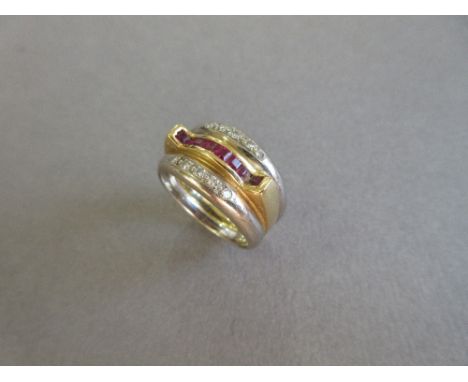 A modern ruby and diamond band ring, the central band of yellow precious metal channel set to the front with calibré cut rubi