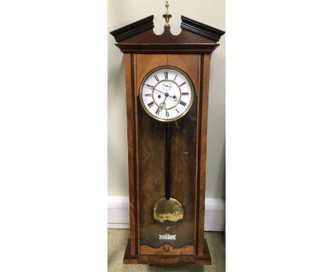 A 19th century walnut Vienna wall clock, the broken pediment with brass finial above typical glazed case, the two part enamel