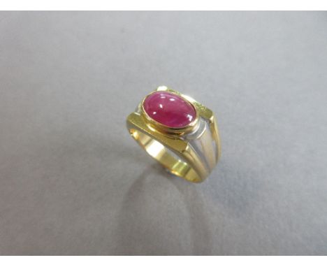 A star ruby single stone ring, the oval cabochon ruby set horizontally in a collet on a flat plane, to broadly reeded shoulde