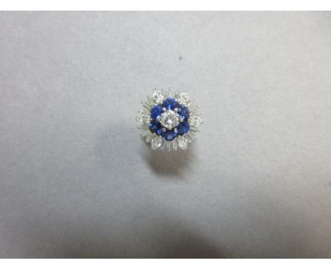 A sapphire and diamond cluster ring, of flowerhead form with a central round brilliant cut diamond in a ring of six round cut