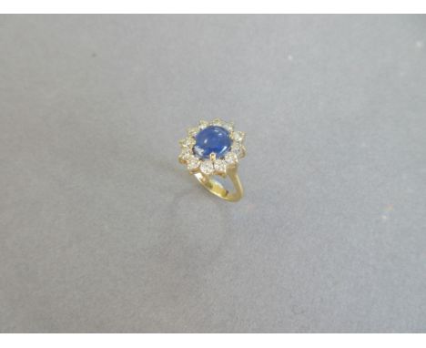 A star sapphire and diamond cluster ring, the oval cabochon mid blue sapphire claw set in a border of twelve round brilliant 