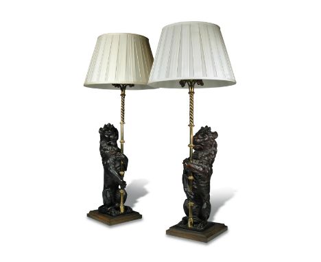 A pair of 19th century carved oak heraldic lions supporting gothic brass lamp holders, the rampant beasts clasping the knoppe