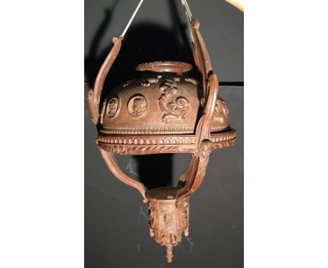 A North European carved wood ceiling light, the dished shade carved with scroll work and classical masks, supported within a 