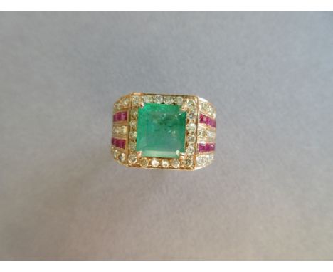 A large emerald, diamond and ruby ring, the 9 x 8mm emerald cut emerald four claw set in a border of round brilliant cut diam