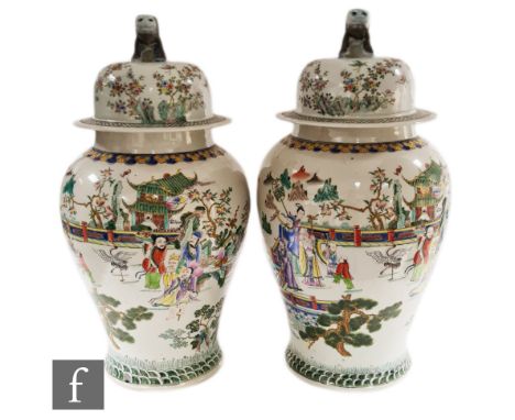 A pair of Chinese porcelain famille rose vases and covers, each of ovoid form, surmounted by a domed cover with shishi finial