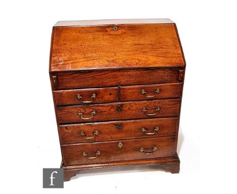 A George III oak bureau of small proportions, the interior fitted with pigeon holes and a well enclosed by a fall over two sh