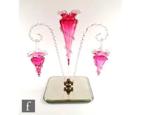 A late Victorian cranberry glass table centre epergne, with central flute flanked by two posy basket branches, all over a mir