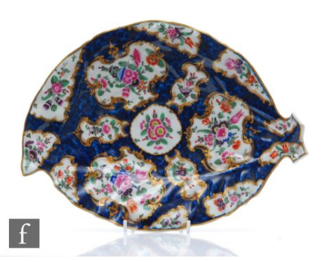 A late 18th Century Worcester blue scale ground leaf shaped dish with hand painted floral cartouche panels with a gilt edge, 