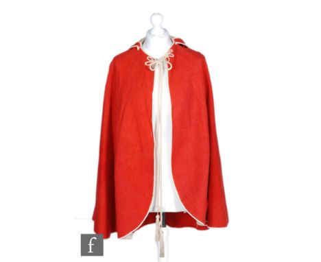 A late 19th to early 20th Century red felt cloak, rope cord detailing, the point hood with three cream tassels, the hood and 