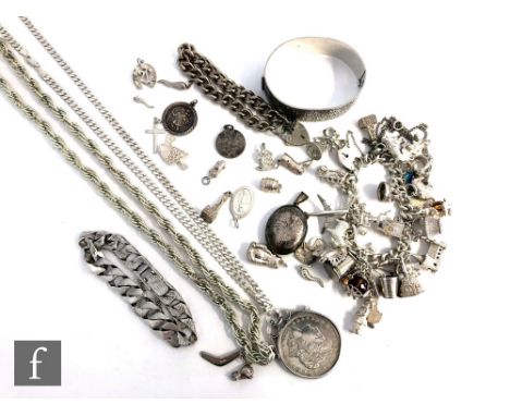 A small parcel lot of assorted silver jewellery to include a bangle, curb and charm bracelets, loose charms, a Liberty Dollar