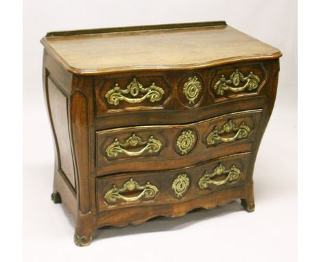 A LOUIS XV STYLE FRENCH OAK SERPENTINE FRONT COMMODE, comprising two short and two long drawers, all with ornate cast brass h