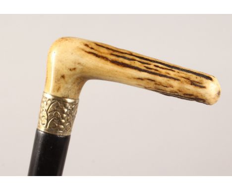 AN ANTLER HANDLED WALKING STICK, with embossed metal collar and ebony shaft. 36ins long.