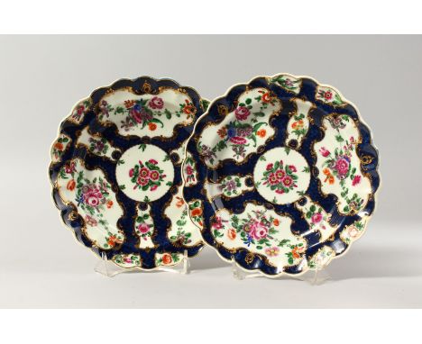 A PAIR OF WORCESTER BLUE SCALE PLATES, finely painted with colourful flowers in gilt panels, fretted square.