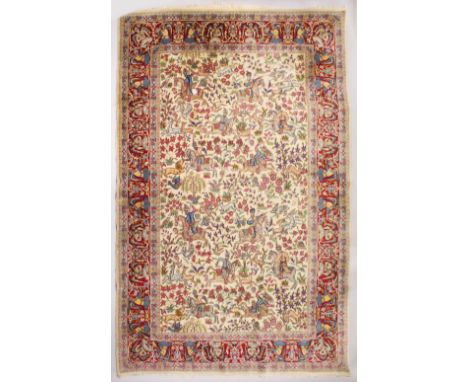 AN INDIAN CARPET, beige ground decorated all-over with a hunting scene, within a red ground border with winged figures. 10ft 