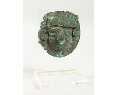 A SOUTH AMERICAN PATINATED COPPER MASK, on Perspex stand.