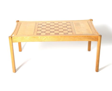 A Light Elm and Ash Chess Top Coffee Table, labelled Ercol Galleries, circa 1980, of rectangular curved form, 107cm by 59cm b