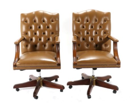 A Pair of Close-Nailed Brown Leather Executive Swivel Office Armchairs, modern, with button back supports and mahogany arm su