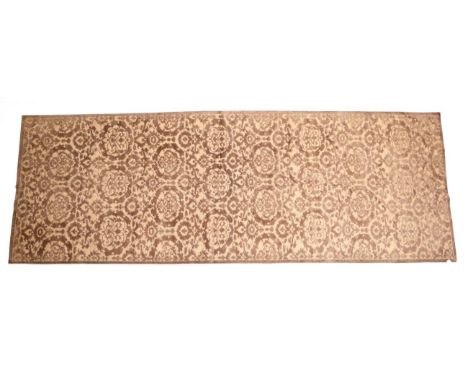 A Modern Brocade Carpet, the light tan lattice field of flowerheads enclosed by plain narrow borders, 538cm by 195cm