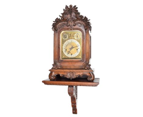 A 19th century German bracket clock with bracket. The oak case has black forest style carving; a crown of roses in a bower on