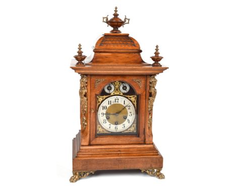 A Victorian walnut bracket clock. The pagoda top has three urn-shaped finials and tiling detail. A pair of brass figureheads 