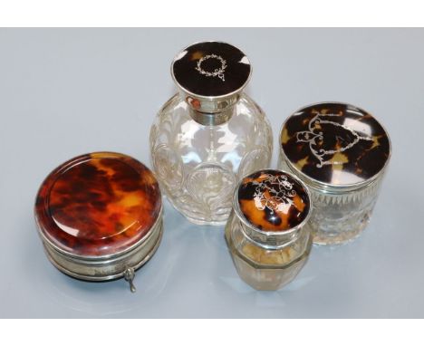 A George V silver and tortoiseshell mounted glass scent bottle, two similar toilet jars and a 1920's silver and tortoiseshell