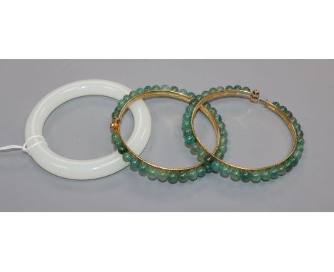 A Chinese white jade bangle and two green stone bangles