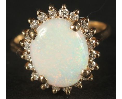 A TRADITIONAL STYLE 14CT YELLOW GOLD CLUSTER RING set with an oval cabochon white opal, surrounded by a halo of RBC diamonds.
