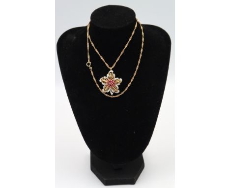 A ruby and single cut diamond cluster flower pendant with brooch fitting. Width 28mm. Weight 7.08 grams. Suspended from a cha