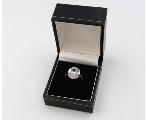 An Art Deco style oval aquamarine and diamond cluster ring. Set with brilliant and baguette cut diamonds. Stamped 18ct and pl