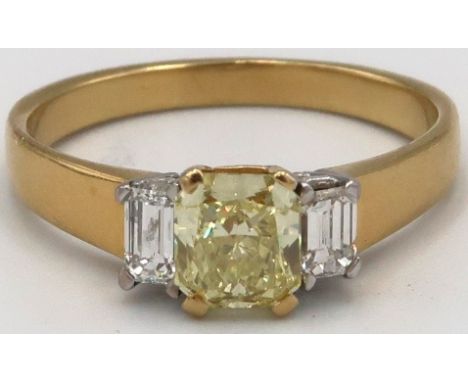 An 18ct yellow gold three stone Diamond ring, the central Fancy Yellow Diamond estimated weight 1.03ct, untested for natural 