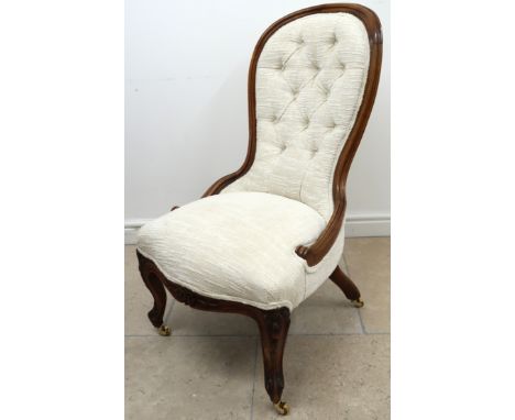 A walnut framed spoon back nursing chair, button upholstery in white raised on casters. 