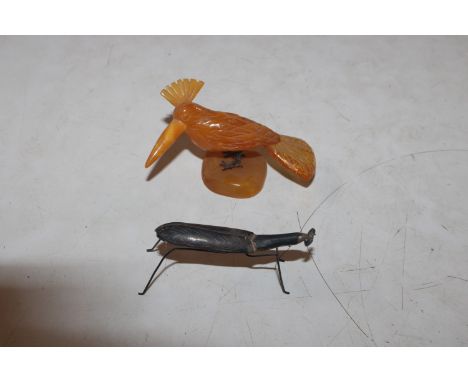 A white metal model of an insect and an amber coloured and white metal model of a bird