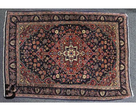 Persian wool carpet. The carpet having a ruby and pink floral design on blue ground, surrounded by a foliate border, approx 1