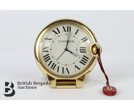 Cartier brass travel clock. The alarm clock having a white face and Roman dial and cabochon winder, approx&nbsp; cms diameter