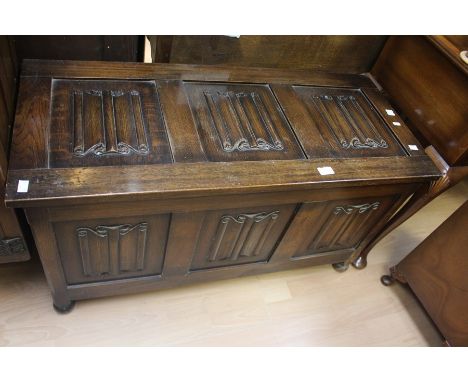 A 20th Century carved oak blanket chest, rectangular lid above three panel front, raised on bun feet.
