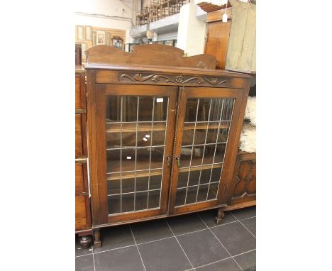 An early 20th century oak glazed bookcase, rectangular top above two panel doors with glazed inlay, turn supports on square f