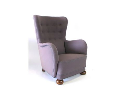 A 1950's Danish cloth and button upholstered armchair on mahogany bun feet