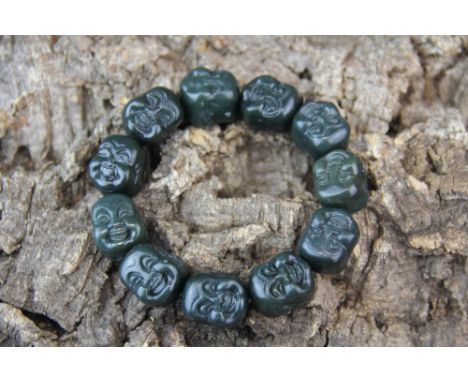 A strand of eleven Chinese carved dark green jade/ hardstone Buddha head beads. Bead size approx. 2cm.