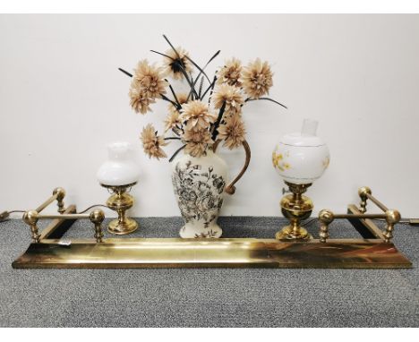 A brass adjustable fender, two brass oil lamp style table lights and a ceramic vase.