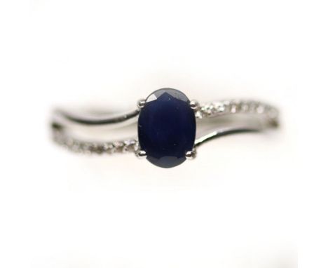 A 925 silver ring set with an oval cut sapphire and white stone set shoulders, (P.5).