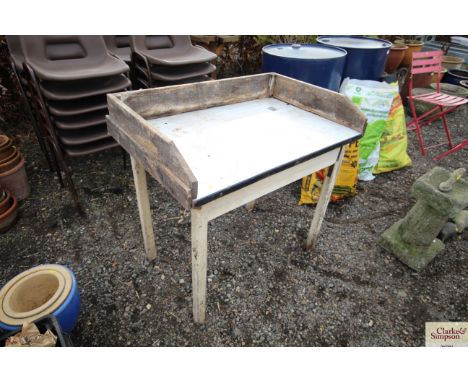 A pine kitchen table with drawer with enamel top recently used for potting up plants