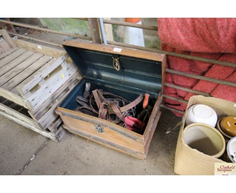 A metal trunk containing various horse tack ; horse brushes etc.